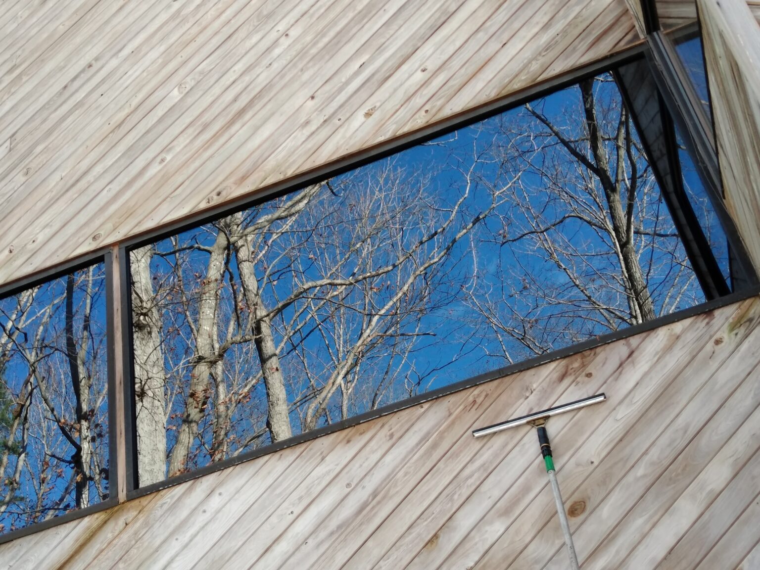 Large residential windows reflecting a clear blue sky after cleaning